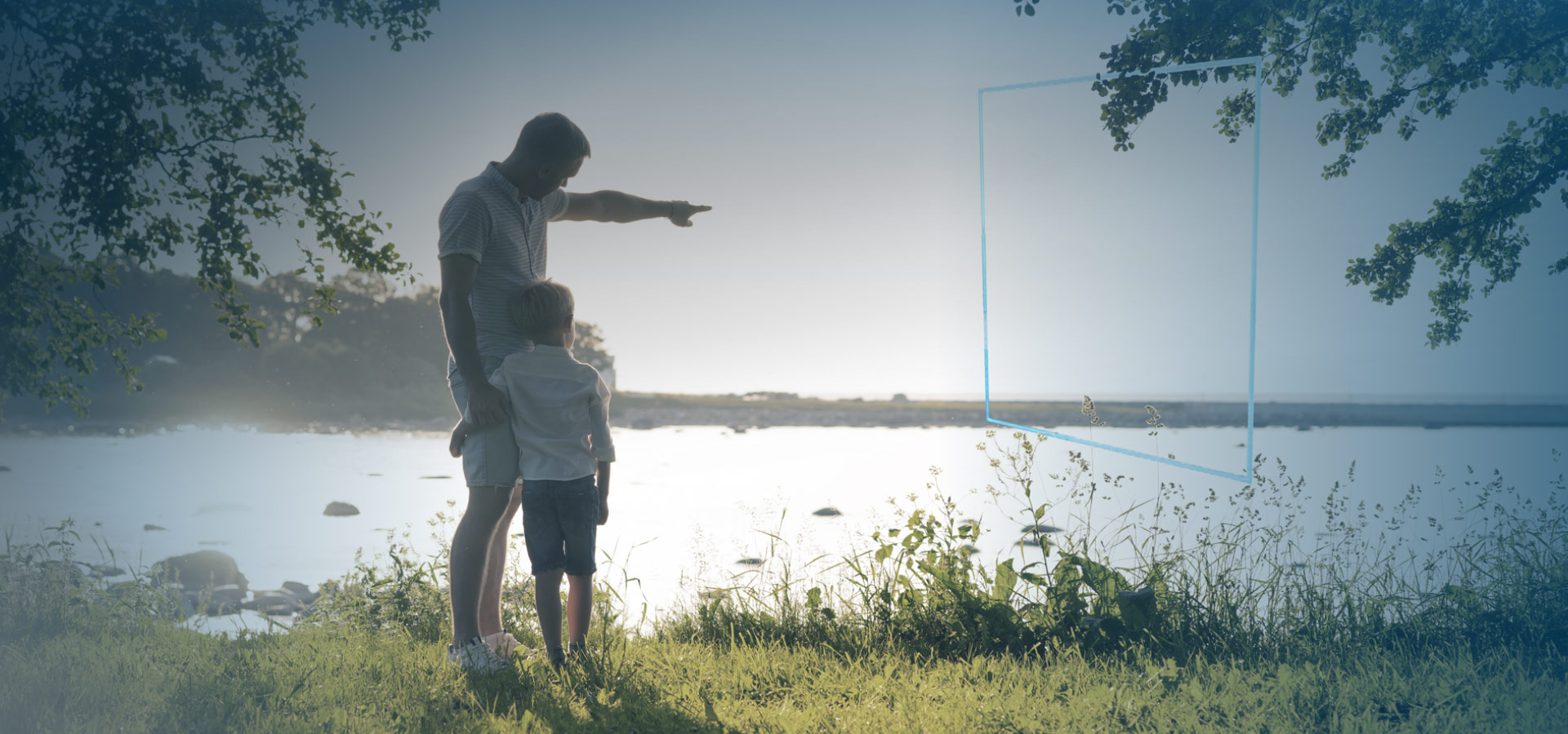 A man stands on the side of a lake with a young boy in his arms. The father is pointing into the distance above the water while his son watches curiously. The sun illuminates the lake's surface and the surrounding trees.